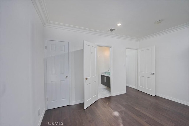 unfurnished bedroom with ornamental molding, dark wood-type flooring, and connected bathroom