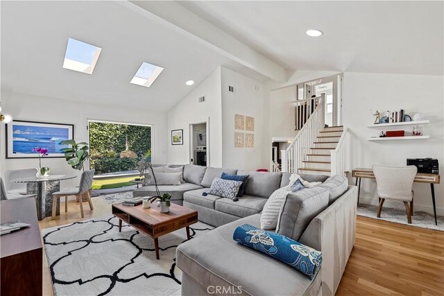 living room featuring light wood-type flooring and vaulted ceiling with beams