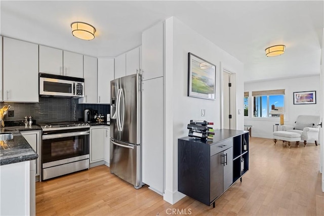 kitchen featuring white cabinetry, backsplash, light hardwood / wood-style flooring, and appliances with stainless steel finishes