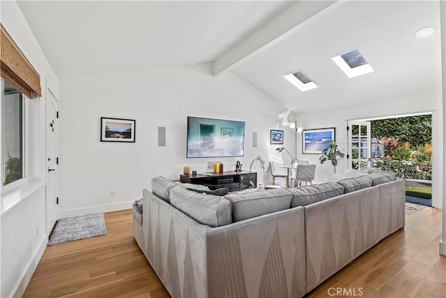 living room featuring lofted ceiling with skylight and light hardwood / wood-style flooring