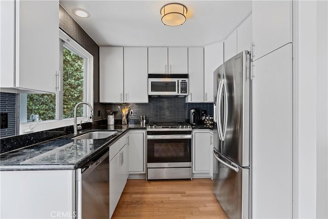 kitchen with stainless steel appliances, sink, white cabinets, and light hardwood / wood-style floors