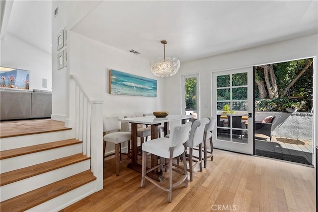 dining room featuring lofted ceiling, light hardwood / wood-style flooring, and a chandelier