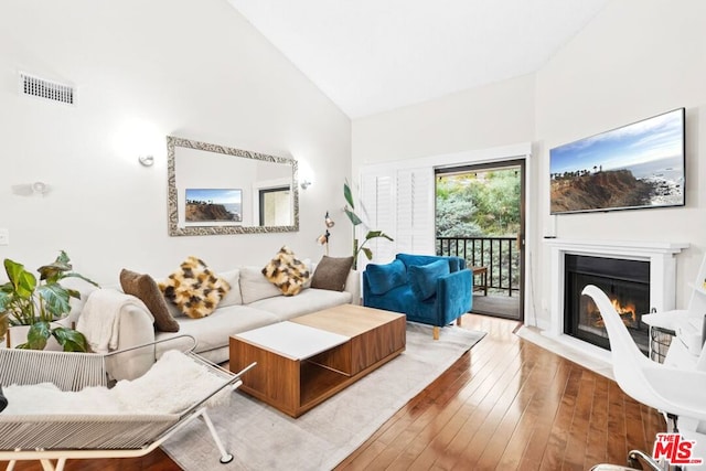 living room featuring high vaulted ceiling and hardwood / wood-style floors