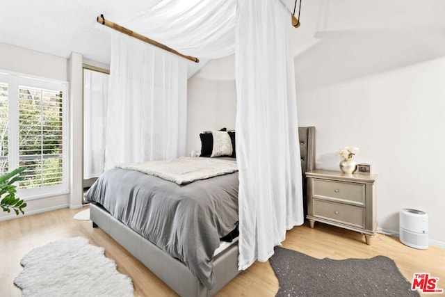 bedroom with light hardwood / wood-style flooring and multiple windows