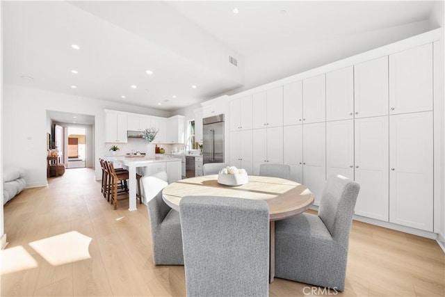 dining space featuring vaulted ceiling and light hardwood / wood-style flooring