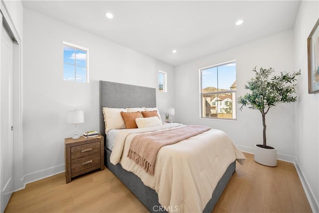 bedroom featuring light wood-type flooring, a closet, and multiple windows