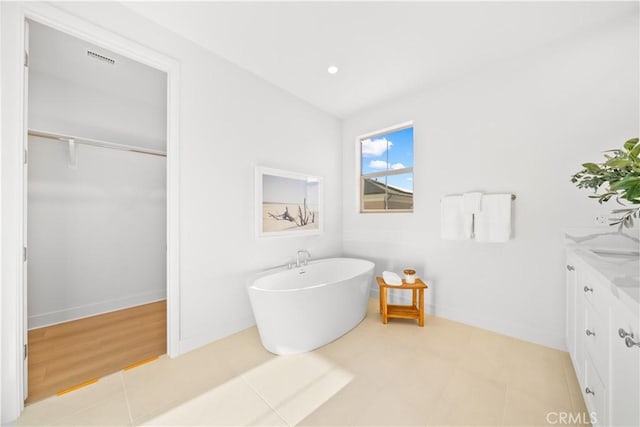 bathroom with vanity, tile patterned flooring, and a tub to relax in