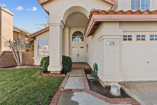 view of exterior entry with a garage and a yard