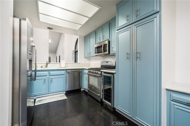 kitchen with stainless steel appliances, dark hardwood / wood-style flooring, pendant lighting, sink, and blue cabinets