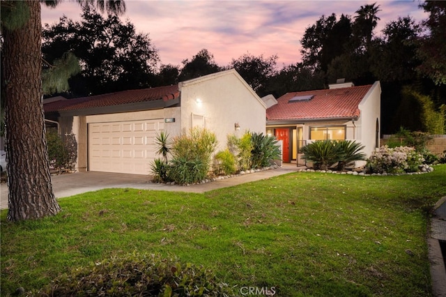 mediterranean / spanish home with a lawn and a garage