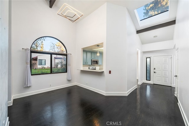 entrance foyer with high vaulted ceiling, dark hardwood / wood-style flooring, a skylight, and beam ceiling