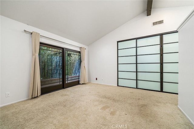 carpeted empty room featuring vaulted ceiling with beams