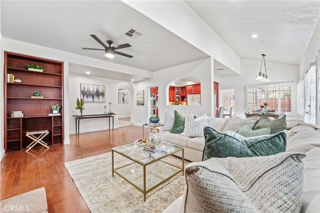 living room with ceiling fan, vaulted ceiling, and wood-type flooring