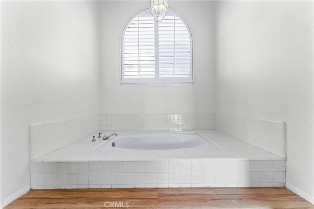 bathroom featuring hardwood / wood-style flooring and tiled bath