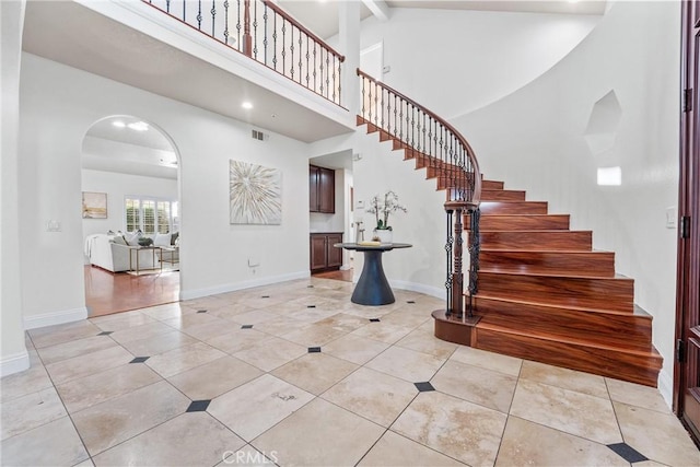 entryway featuring beamed ceiling, light tile patterned floors, and high vaulted ceiling