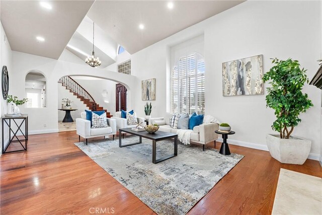 living room with hardwood / wood-style flooring, high vaulted ceiling, and a chandelier