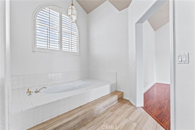 bathroom with tiled tub and hardwood / wood-style floors