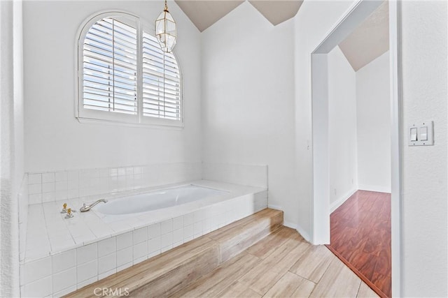 bathroom featuring tiled bath and hardwood / wood-style floors