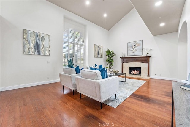 living room with hardwood / wood-style flooring, a fireplace, and high vaulted ceiling