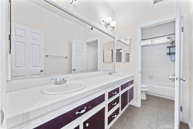 full bathroom featuring vanity, tiled shower / bath, tile patterned floors, and toilet