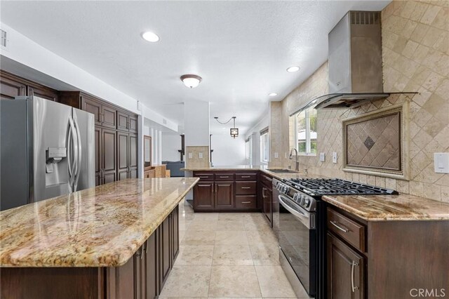 kitchen featuring light stone counters, sink, wall chimney exhaust hood, and appliances with stainless steel finishes