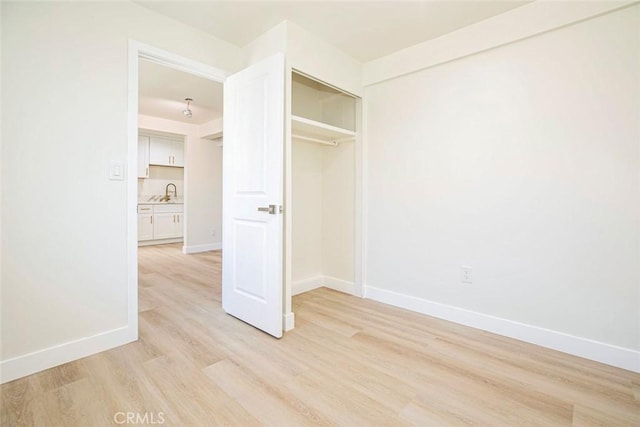 unfurnished bedroom featuring light wood-type flooring, a closet, and sink