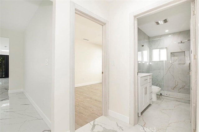 bathroom featuring a tile shower, vanity, and toilet