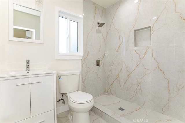 bathroom featuring tiled shower, vanity, and toilet