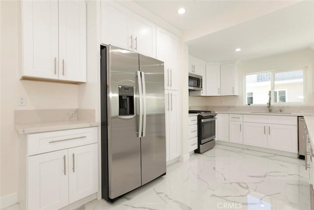 kitchen with stainless steel appliances, white cabinetry, and sink