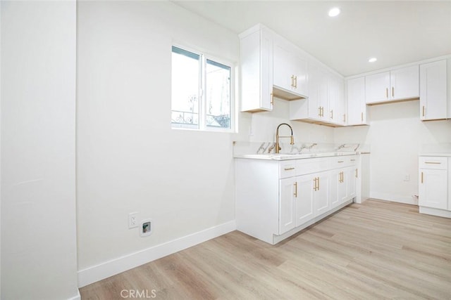 kitchen with sink, white cabinetry, and light wood-type flooring