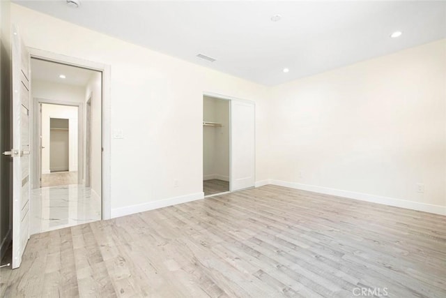 unfurnished bedroom with light hardwood / wood-style floors and a closet