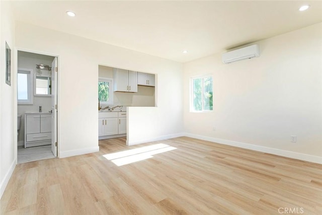 unfurnished living room with a wall mounted AC and light hardwood / wood-style flooring