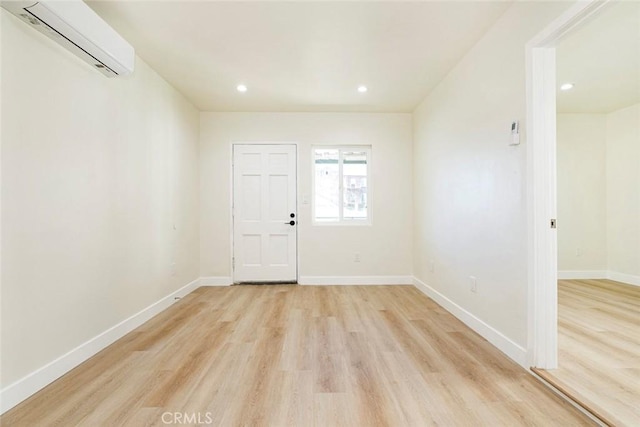 empty room with light hardwood / wood-style floors and a wall mounted AC