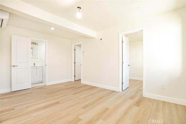 empty room with an AC wall unit, beam ceiling, and light hardwood / wood-style flooring