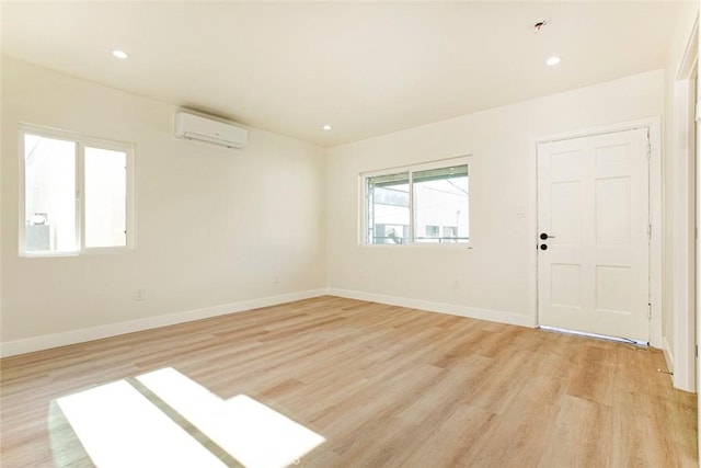 unfurnished room featuring an AC wall unit and light wood-type flooring