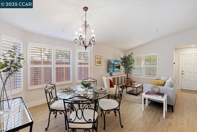 dining area featuring lofted ceiling, light hardwood / wood-style flooring, plenty of natural light, and a notable chandelier