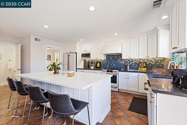 kitchen with white appliances, a kitchen island, white cabinetry, sink, and custom range hood