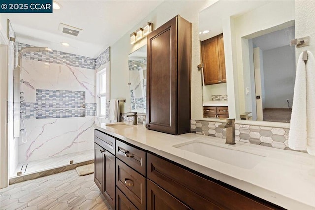 bathroom with tile patterned flooring, a tile shower, and vanity