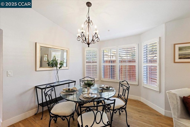 dining area featuring vaulted ceiling, a chandelier, and light hardwood / wood-style flooring