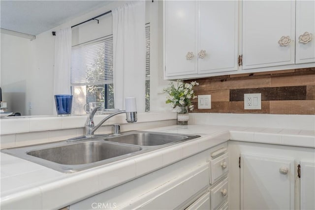 kitchen with white cabinetry, tile counters, and a sink