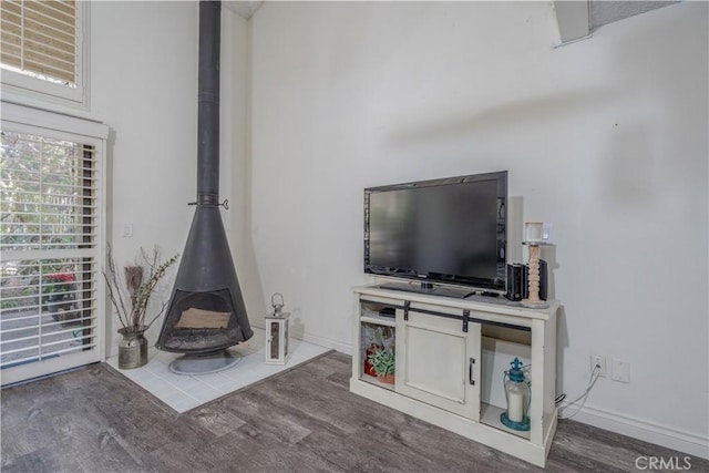 unfurnished living room with baseboards, wood finished floors, and a wood stove