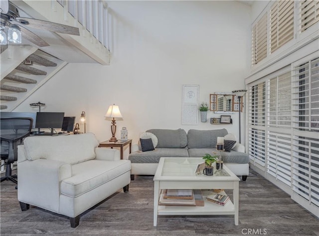 living room featuring stairs, a ceiling fan, wood finished floors, and a towering ceiling