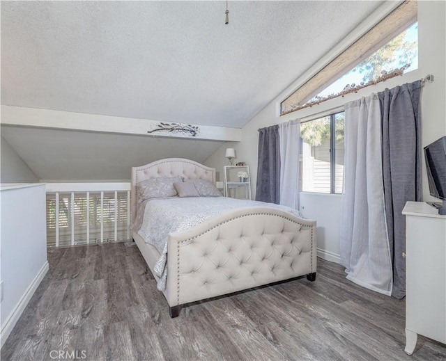 bedroom with vaulted ceiling, wood finished floors, baseboards, and a textured ceiling