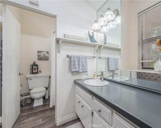 bathroom with baseboards, toilet, wood finished floors, and vanity