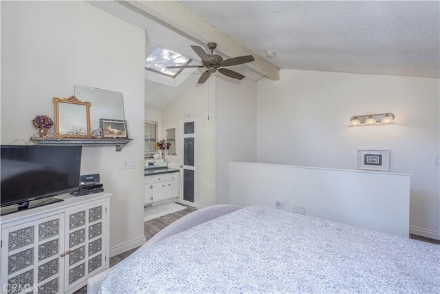 bedroom featuring lofted ceiling with skylight, baseboards, ensuite bathroom, and a textured ceiling