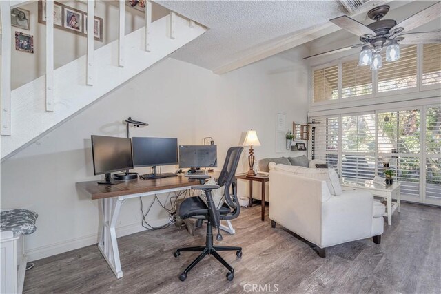 office area featuring a towering ceiling, hardwood / wood-style floors, a textured ceiling, and ceiling fan