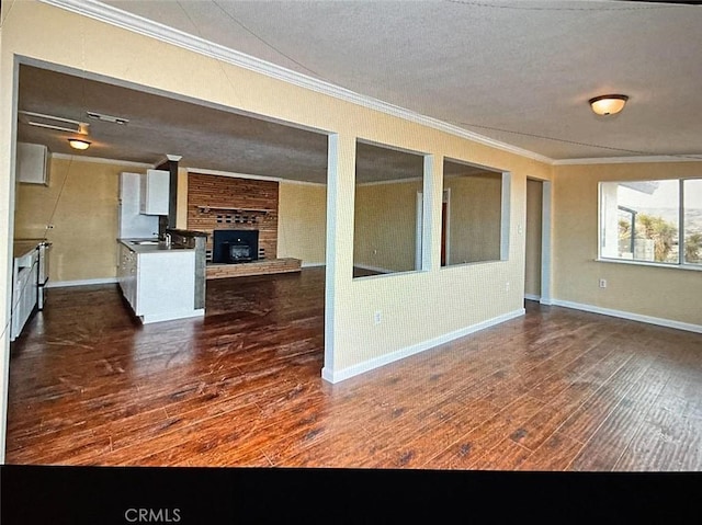 unfurnished living room with a textured ceiling, brick wall, crown molding, and dark hardwood / wood-style floors