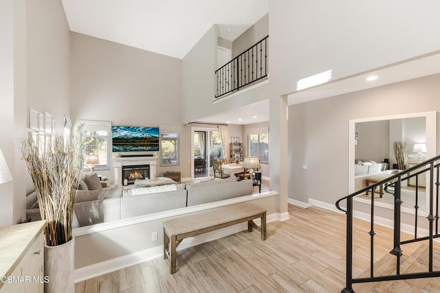 living room with light hardwood / wood-style floors and high vaulted ceiling