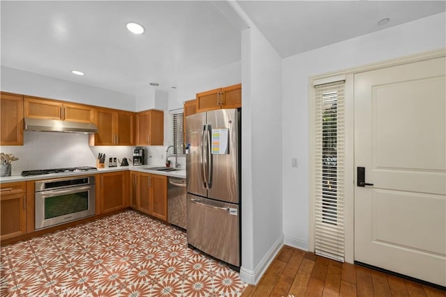 kitchen with light wood-type flooring, appliances with stainless steel finishes, decorative backsplash, and sink