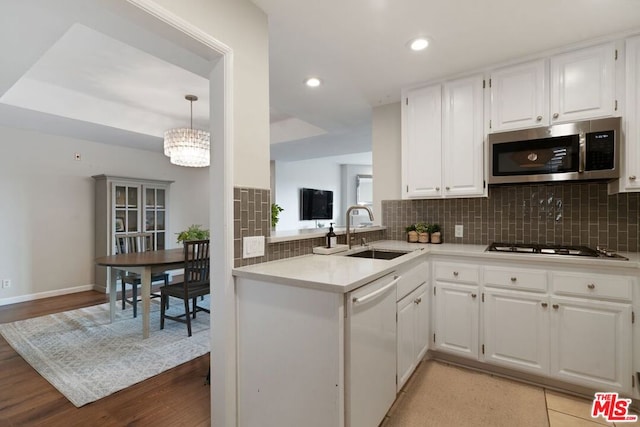 kitchen featuring hanging light fixtures, decorative backsplash, white cabinets, appliances with stainless steel finishes, and sink